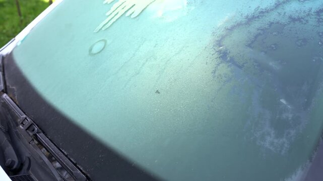 Slow pan shot, frozen, melting ice on windshield at late spring, bizzare wheather condition.