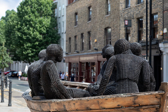 LONDON, UK - JULY 23, 2021:  Wooden Boat With Seven People statue (by Kalliopi Lemos) in Spitalfields