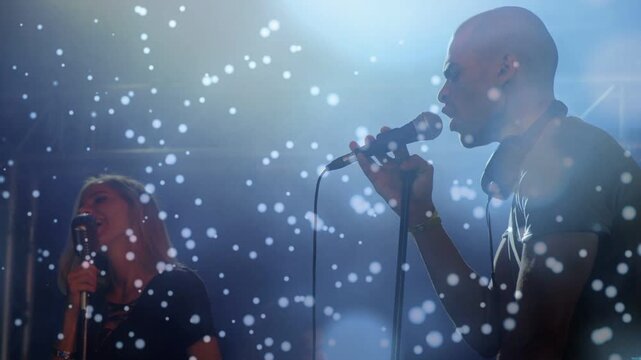 Singer leaning into mic, singing and gesturing, camera widening, confetti falling over music act