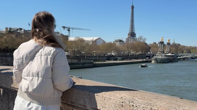 Tranquil female traveler admiring iconic skyline along Seine in sunshine