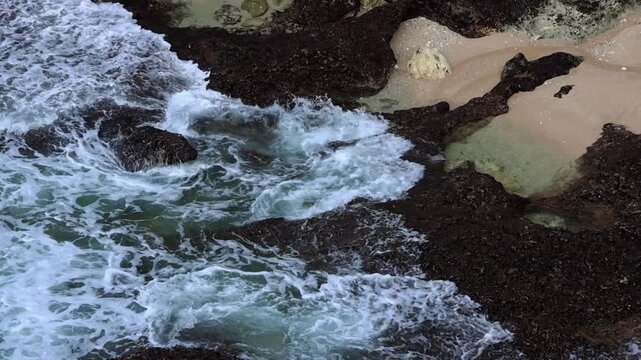 Cliffside View of Waves Washing Over Rocky Shore in Bali