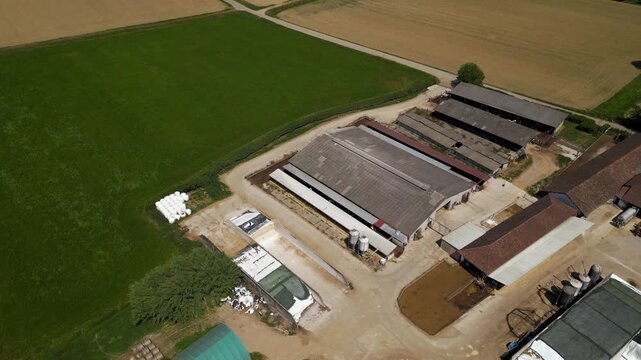 Aerial View of a Rural Farm: An expansive aerial perspective showcases a working farm nestled within a patchwork of green fields and agricultural land.