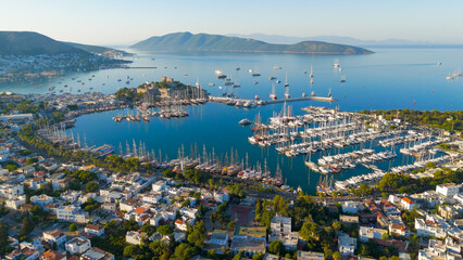 Naklejka premium Bodrum, Turkey. Scenic coastal view from shore of Gokova Bay with Bodrum Castle, yacht marina, mountains and white houses in foreground.. Aerial View
