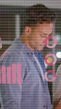 Vertical video: Two coworkers tapping tablet, reviewing data as pink finance charts obscuring view