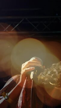 Vertical video: Singer holding mic, starting music, engaging crowd while lens flare veiling face
