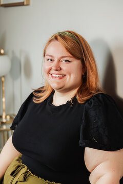 Joyful woman smiling in warm light with gold lamp in background