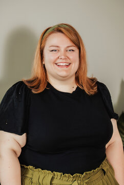 Woman with bright smile, black eyelet top, neutral background