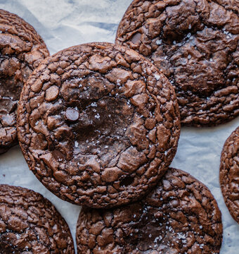 Close up of freshly baked chocolate brownie cookies on parchment.
