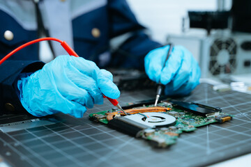 Obraz premium Technical hardware repair. Hands in blue gloves using multimeter probes to test a computer circuit board, emphasizing precision engineering
