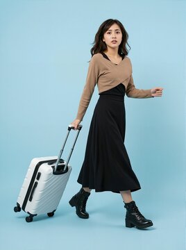 Young woman walking with luggage against blue background