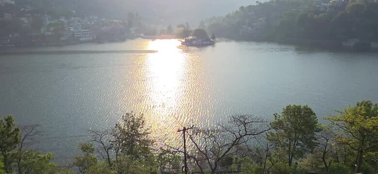 Warm sunset light reflects beautifully across calm Bhimtal Lake waters with peaceful surroundings