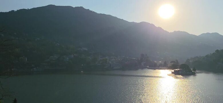 Setting sun shines over lake waters with hills creating a calm scenic moment