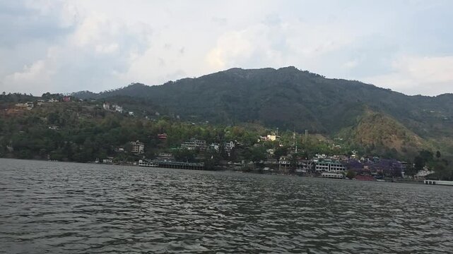 Open view of Bhimtal Lake with blue sky and soft clouds above hills