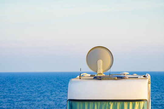 Caravan with satellite dish on roof camping on sea