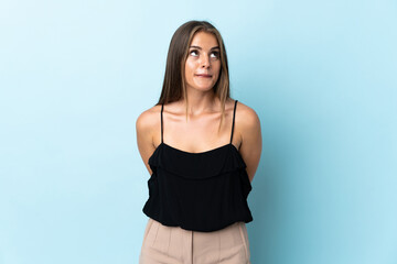 Obraz premium Young Uruguayan woman isolated on blue background and looking up
