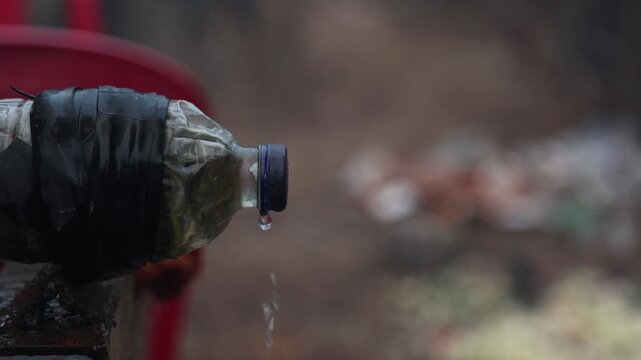 Raw 4K footage of a plastic bottle attached to a tanker outlet as a jugaad, allowing controlled water flow, showing rural innovation and practical solution in India.