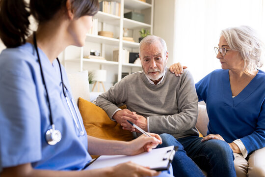 Doctor visiting senior couple at home taking notes about their health status