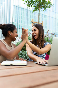 Diverse women collaborating and celebrating success with a high five