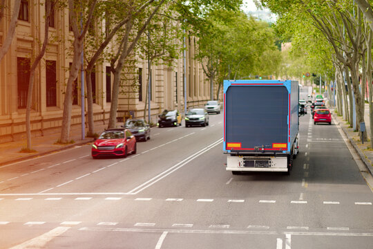 Blue Delivery Box Truck Driving on Tree Lined City Boulevard