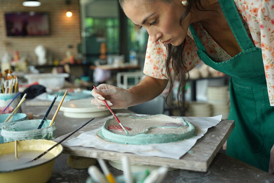 A young woman makes a ceramic plate in a workshop