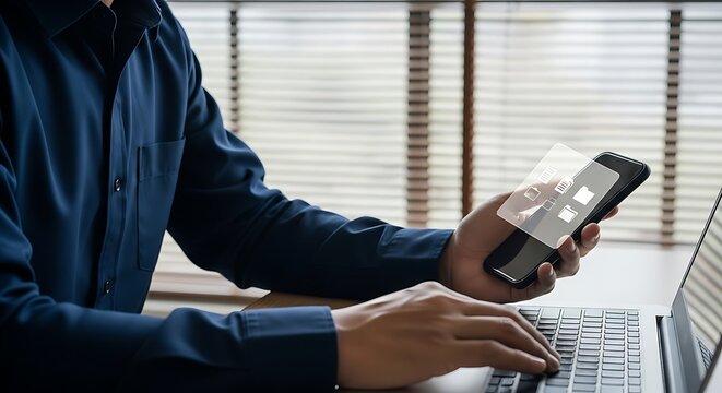 Man in blue shirt using smartphone and laptop computer with transparent screen overlay