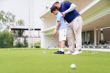 Fototapeta premium Golf instructor teaching young student to putt at practice green