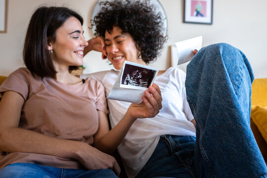 Happy lesbian couple celebrating pregnancy looking at sonogram