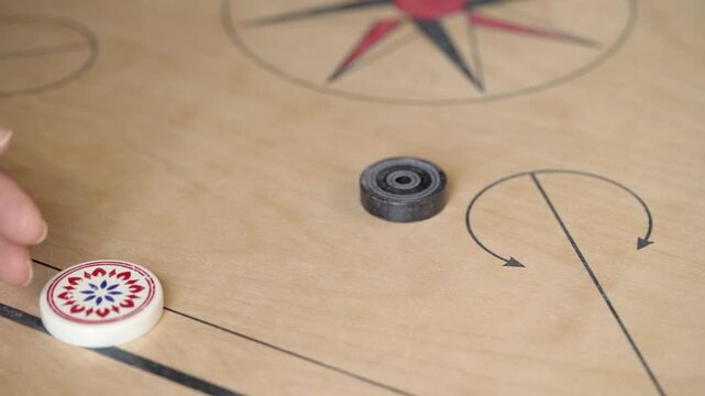 : Close Up of Woman Hand Striking Black Coin with Striker on Carrom Board in Slow Motion
