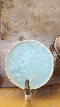 Raw 4K footage of water filling a bucket from a pipe, showing daily water usage, simple rural lifestyle, and basic resource collection in an Indian village.
