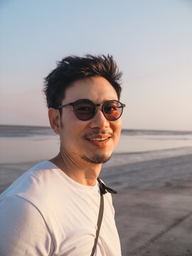 Smiling man wearing shades records lively coast experience