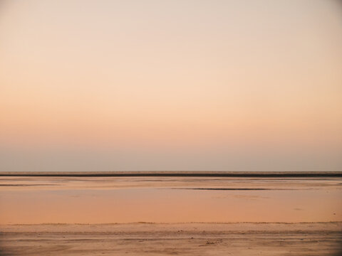 Tranquil sunrise with soft colors reflected on moist beach surface