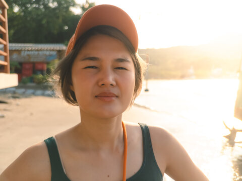 Asian woman traveler smiling in goldenhour beach portrait