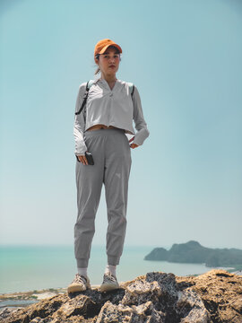 Independent traveler standing by rocky shoreline under bright sky