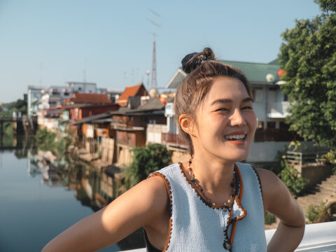 Charming Asian woman exploring vibrant riverside village atmosphere