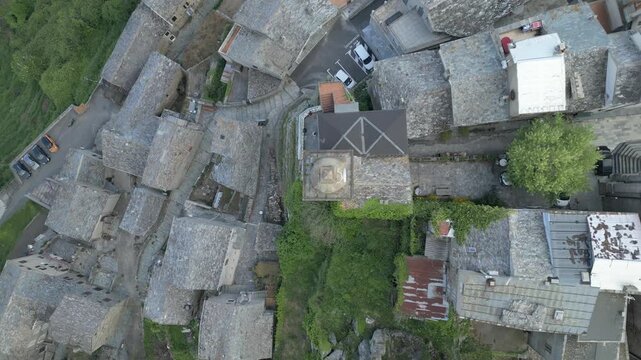 Aerial top down drone pull back reveal of Loreto di Casinca village rooftops under low clouds, Corsica