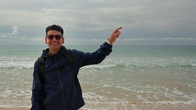 Man Looking at Camera Pointing to Side on Beach representing User Guidance, Service Promotion and Interactive Marketing