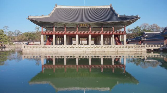 Gyeongbokgung Palace in Seoul South Korea features traditional Korean pavilion with curved tile roof and red columns standing over tranquil pond with perfect mirror reflection on clear day.