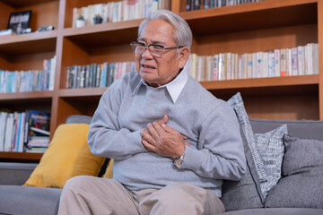 Fototapeta premium Elderly man grab his chest with hand suffer from chest pain in a living room