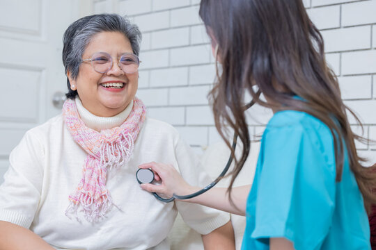 Senior woman smiles during health checkup while nurse uses stethoscope