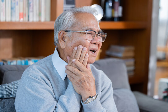 Elderly man grab his cheek suffer from toothache at home