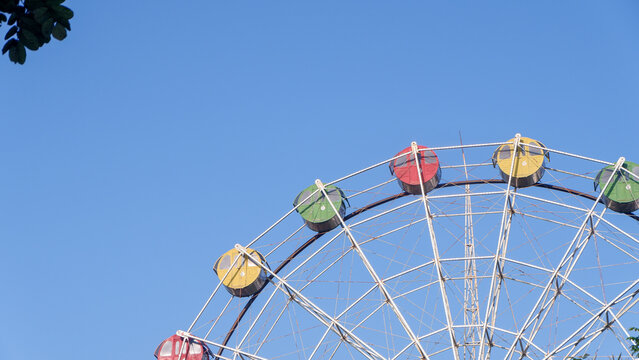 
A big colorful ferris wheel stands high against a clear blue sky in a summer amusement park, offering a fun carnival ride and festive leisure attraction at the holiday fair