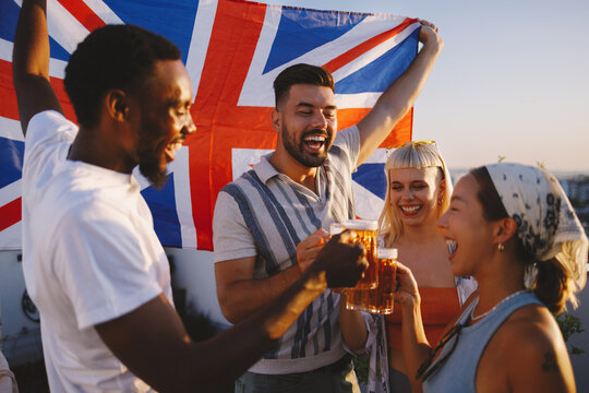 Diverse friends celebrating with beer and union jack flag