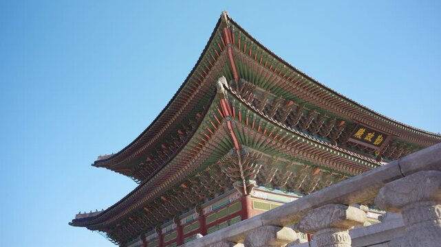 Gyeongbokgung Palace in Seoul South Korea displays intricate traditional Korean roof architecture with colorful dancheong patterns and ornate wooden brackets beneath clear blue sky.