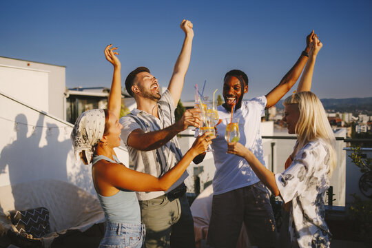 Diverse friends cheering drinks celebrating rooftop party