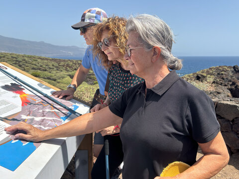 Senior Friends Reading Interpretive Map at Coastal Park While Enjoying Outdoor Sightseeing And Travel