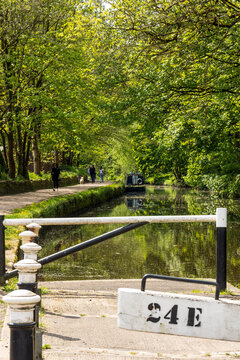 View along the Huddersfield Narrow Canal from lock 24E showing the canal and tow path on a sunny spring day