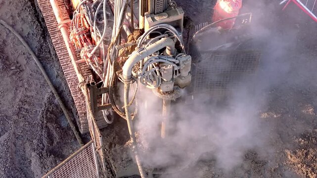 Heavy machinery works on construction site in early morning light creating dust and smoke