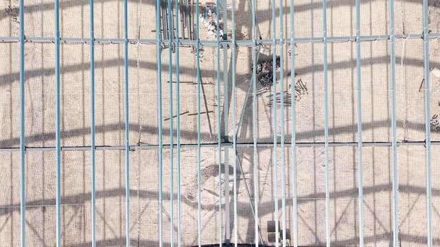 Workers construct a building frame in a large construction site during daytime hours