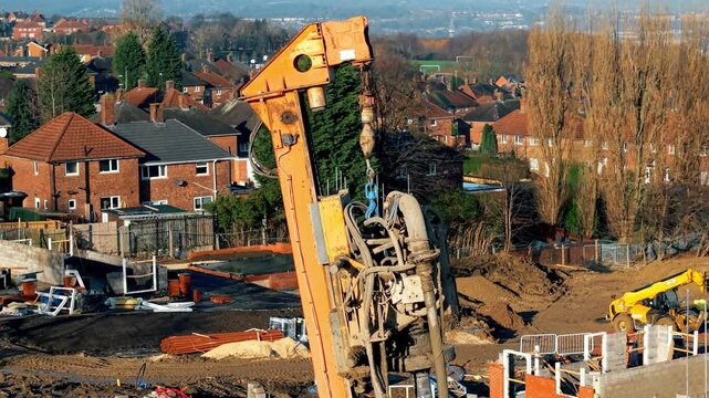 Construction equipment works on site at housing development in city during sunny day