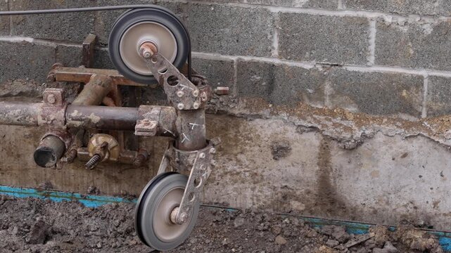 Wheels move along a track near a wall at a construction site during the day